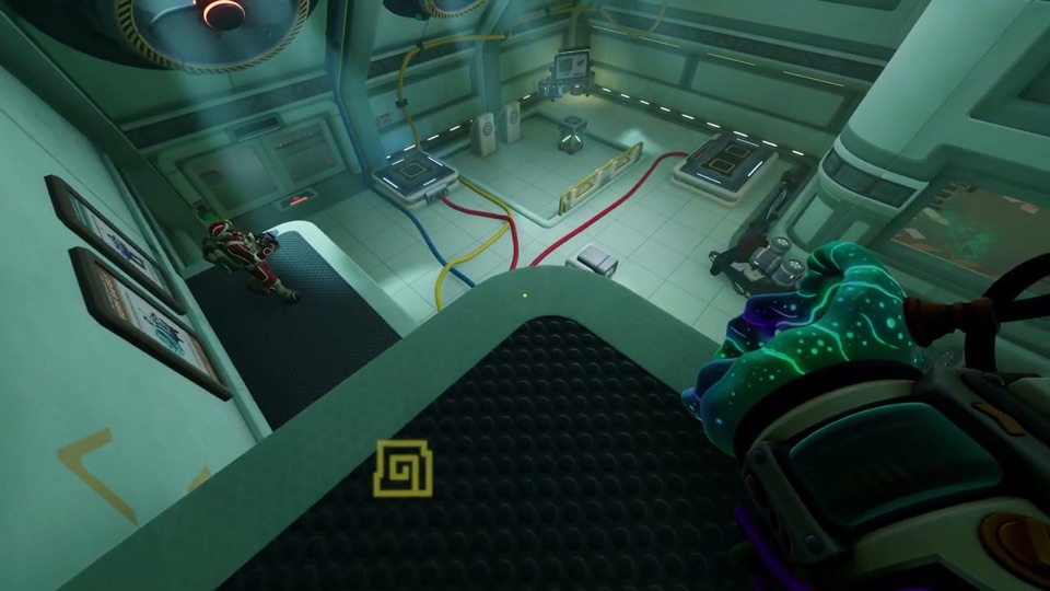 Overview of the test room from a ledge: red, yellow and blue cables run across the floor to square pads, with the red-suited partner standing below