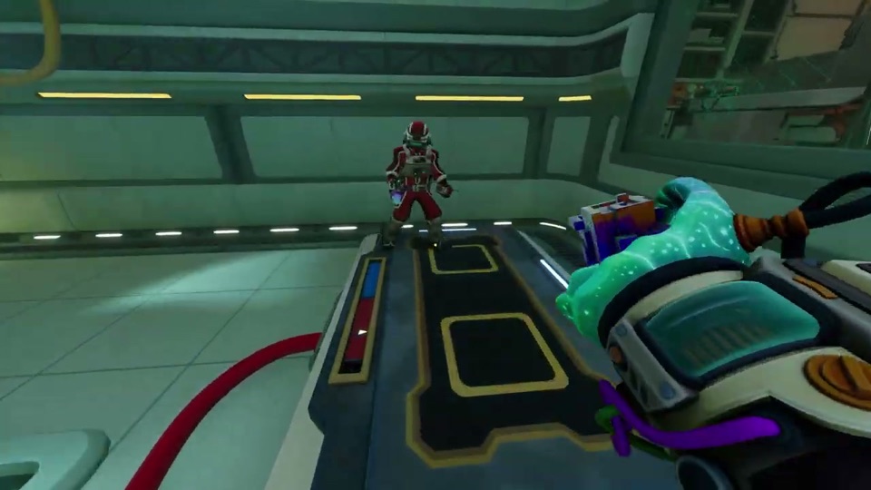 The red-suited partner standing on a pressure plate with a red indicator strip, the red cable leading to it
